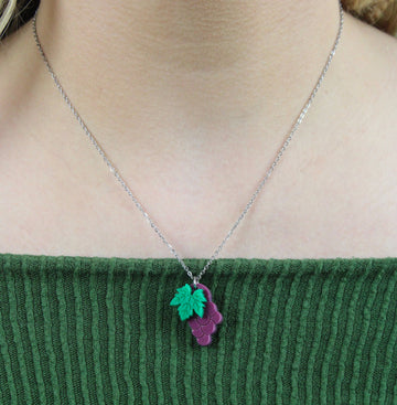 Model wearing necklace featuring acrylic purple grapes on stainless steel chain
