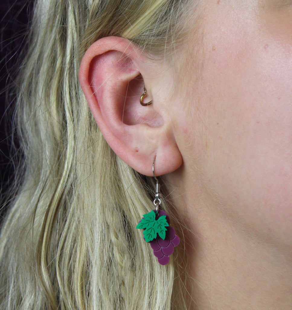 Model wearing arcrylic earrings featuring a bunch of purple grapes and the stem