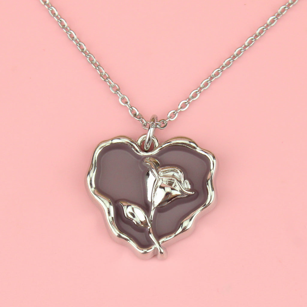a base metal pendant with a beautiful rose in the centre of a purple heart, suspended from sleek stainless steel chains