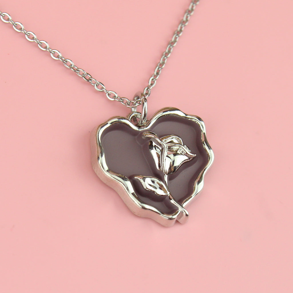 a base metal pendant with a beautiful rose in the centre of a purple heart, suspended from sleek stainless steel chains