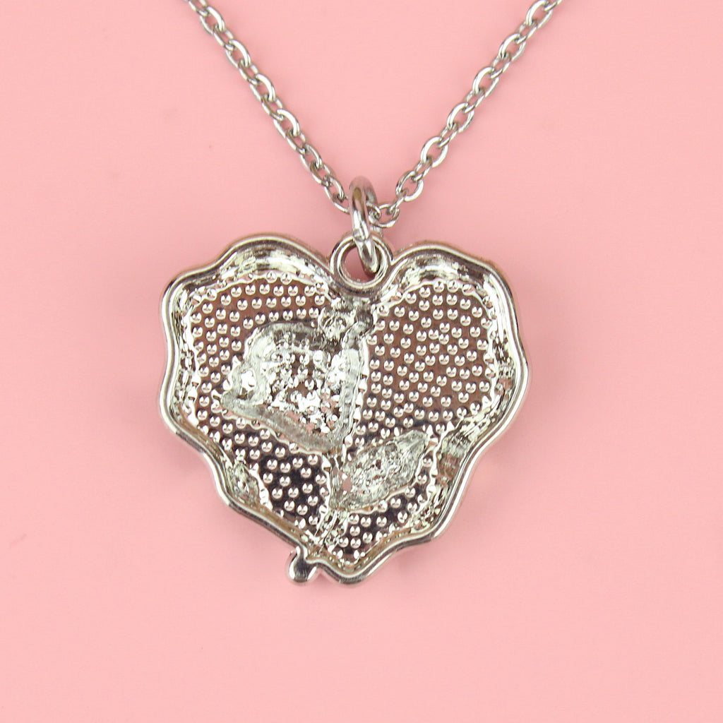 a base metal pendant with a beautiful rose in the centre of a purple heart, suspended from sleek stainless steel chains
