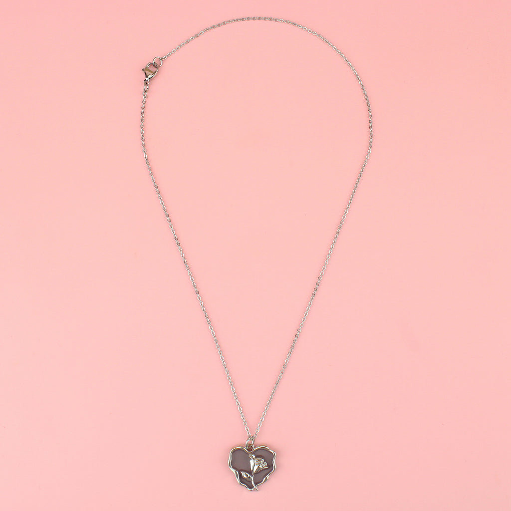 a base metal pendant with a beautiful rose in the centre of a purple heart, suspended from sleek stainless steel chains