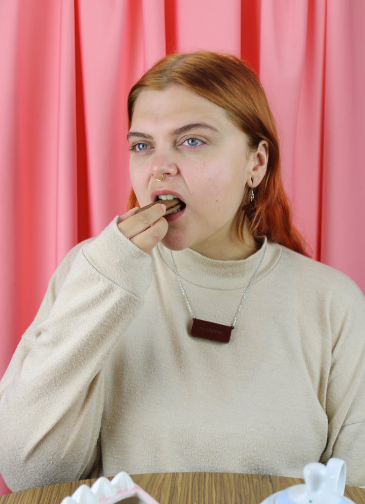 Person eating a cookie in front of a pink curtain
