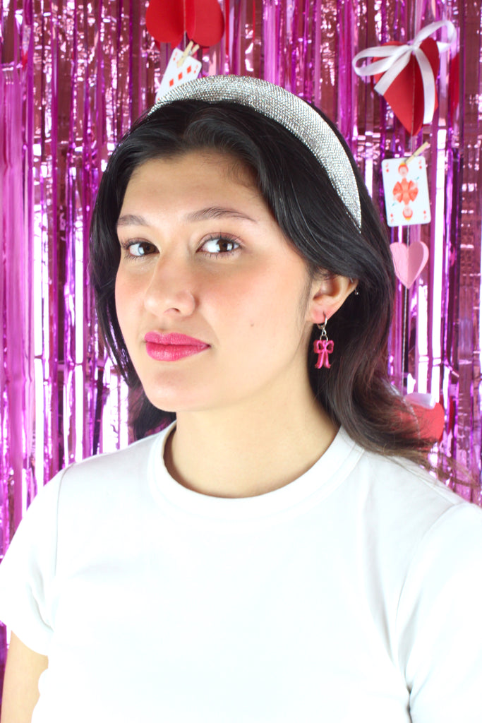 Model wearing Mini pink marble bow charms on stainless steel huggie hoops