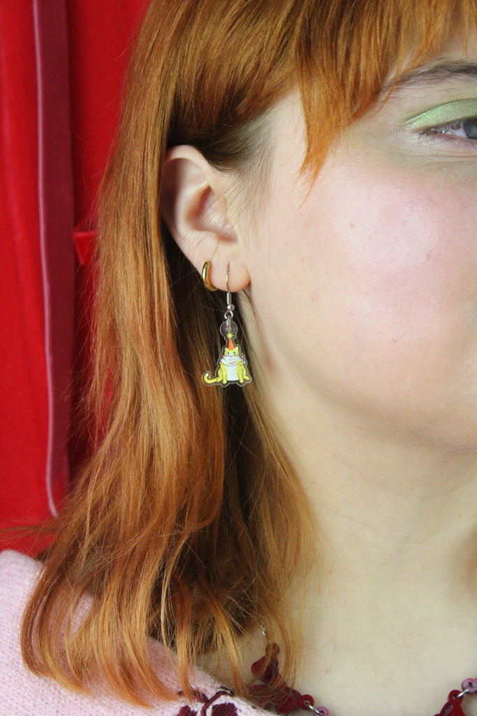 Close-up of a person wearing a cat earring with a red background