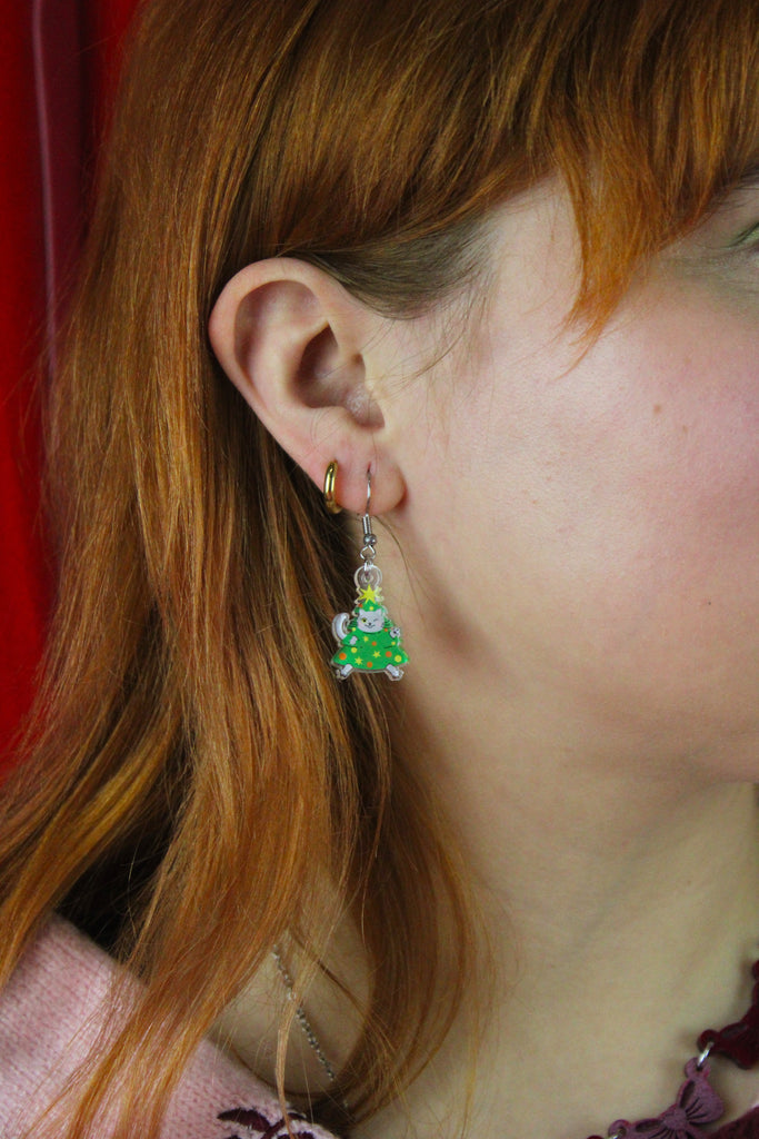 Close-up of a person wearing a cat earring with a red background