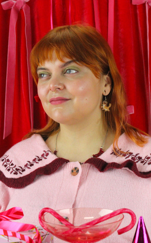 Woman wearing a pink sweater with a red background