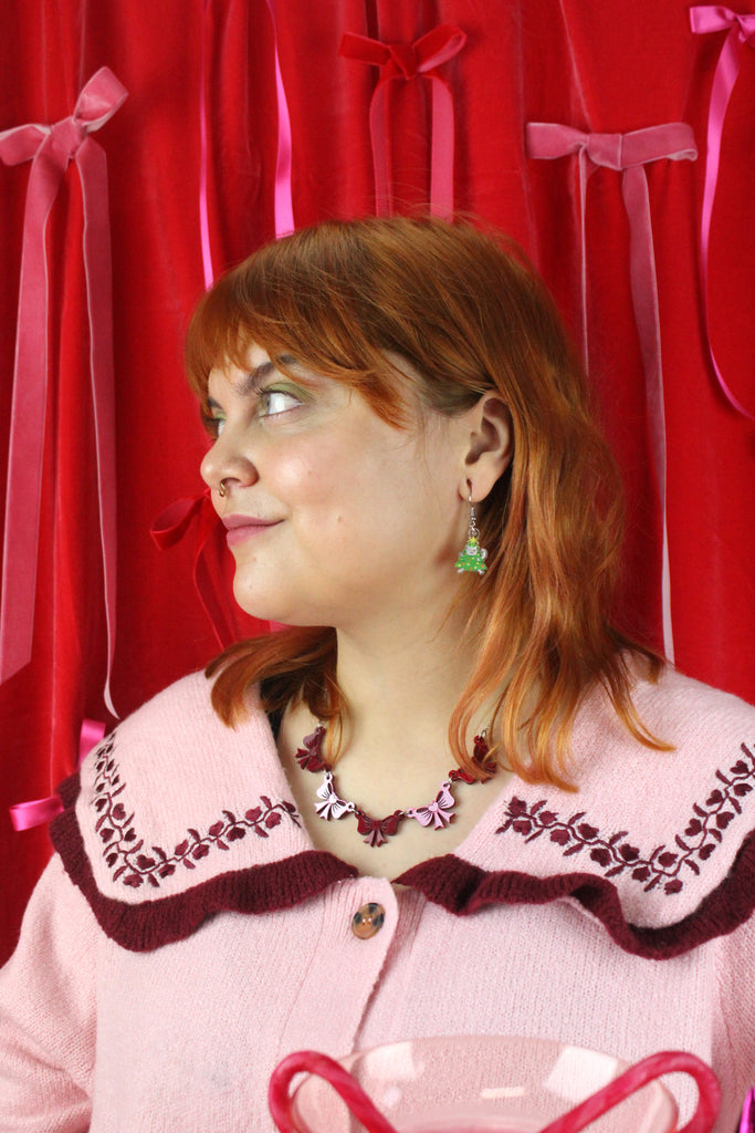 Woman wearing a pink sweater with red ribbons and bows in the background