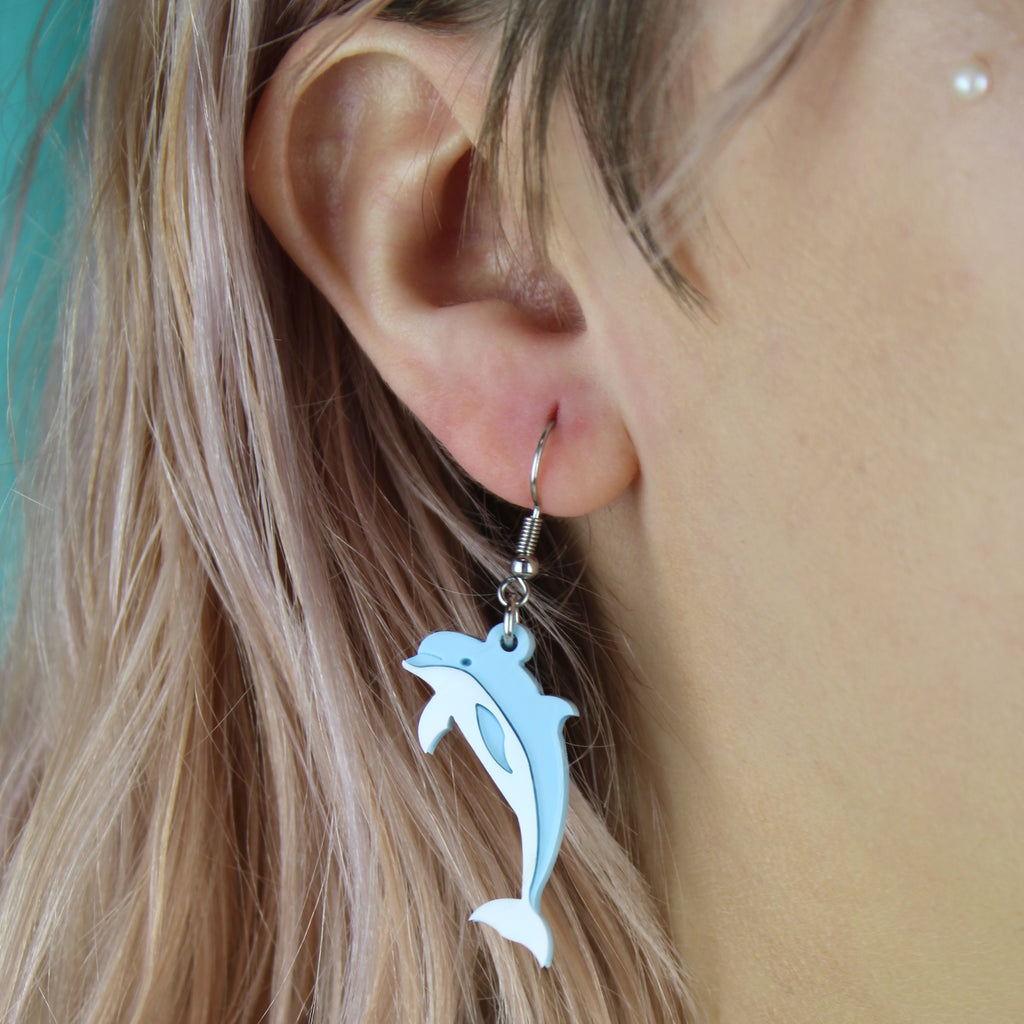 Model wearing Light blue acrylic Dolphin charms on stainless steel earwires