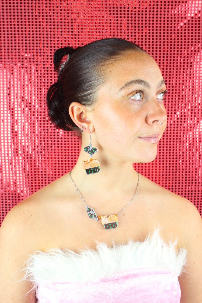 Model wearing earrings that feature a cat sat in a gift box on stainless steel earwires. Worn with the matching necklace 