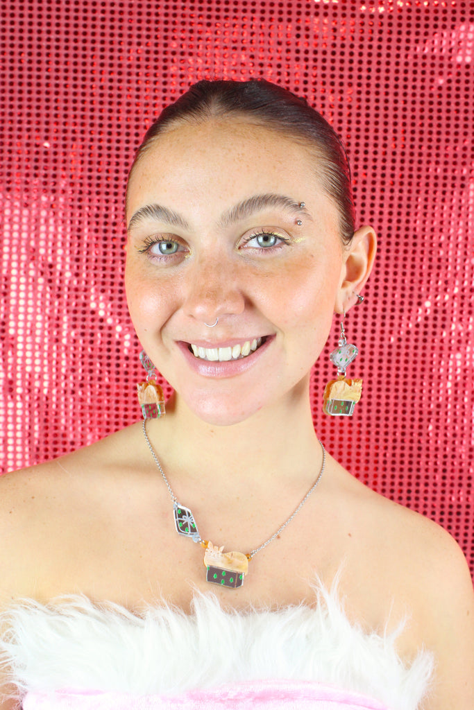 Model wearing earrings that feature a cat sat in a gift box on stainless steel earwires. Worn with the matching necklace 