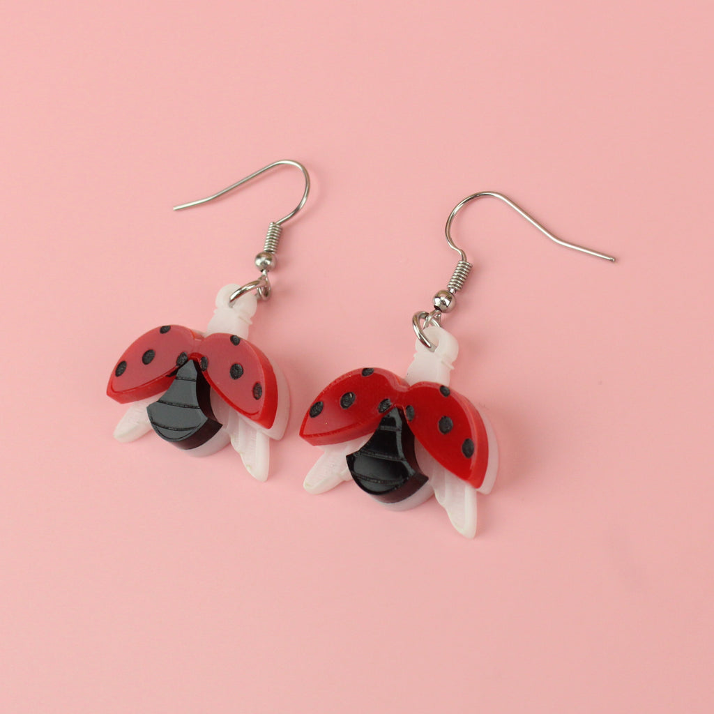 Acrylic charms showing a ladybird spreading its wings on stainless steel earwires