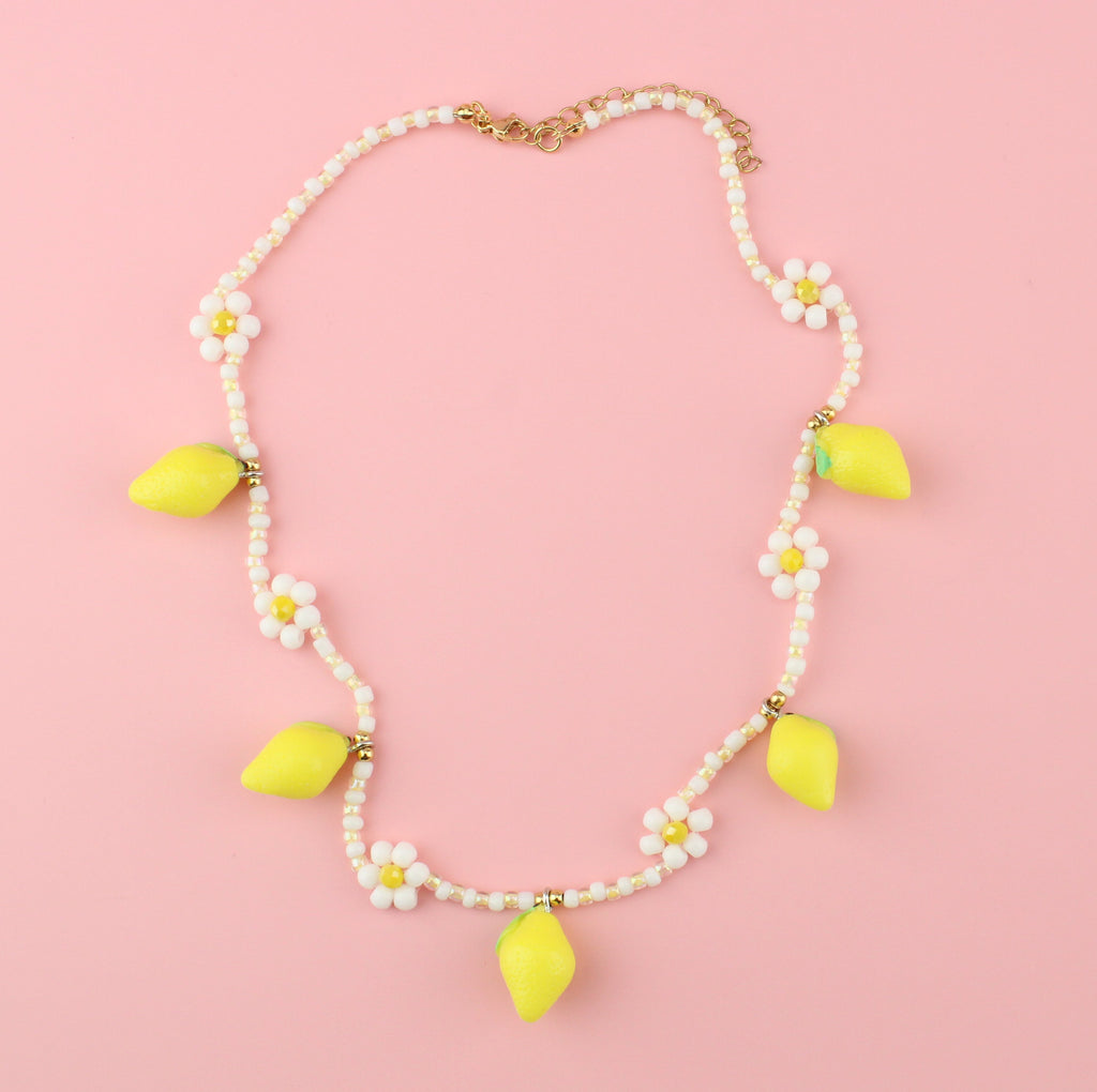 Resin lemon charms on a necklace with glass beads forming a daisy design and a gold plated stainless steel clasp