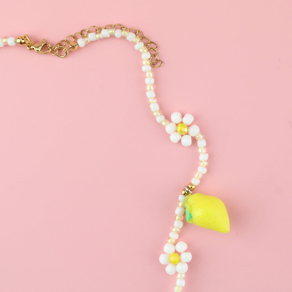 Resin lemon charms on a necklace with glass beads forming a daisy design and a gold plated stainless steel clasp