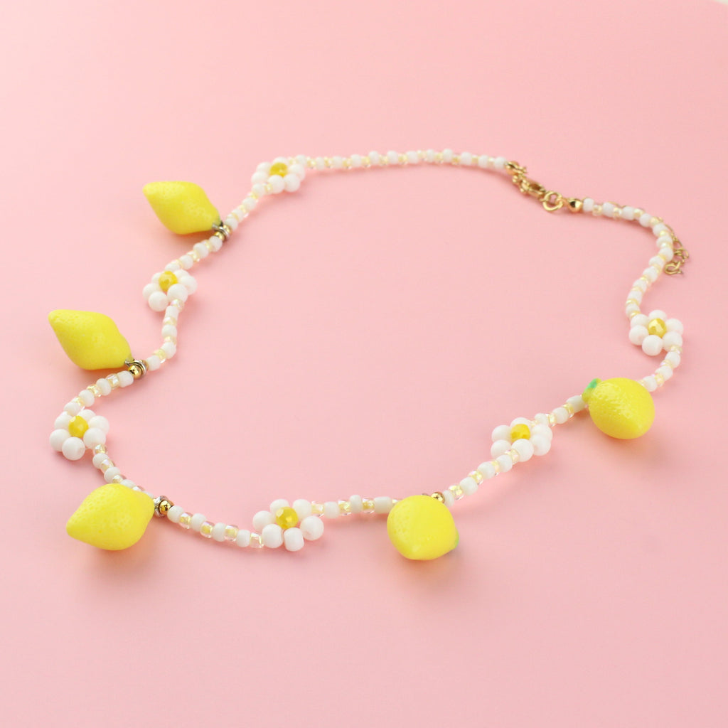 Resin lemon charms on a necklace with glass beads forming a daisy design and a gold plated stainless steel clasp