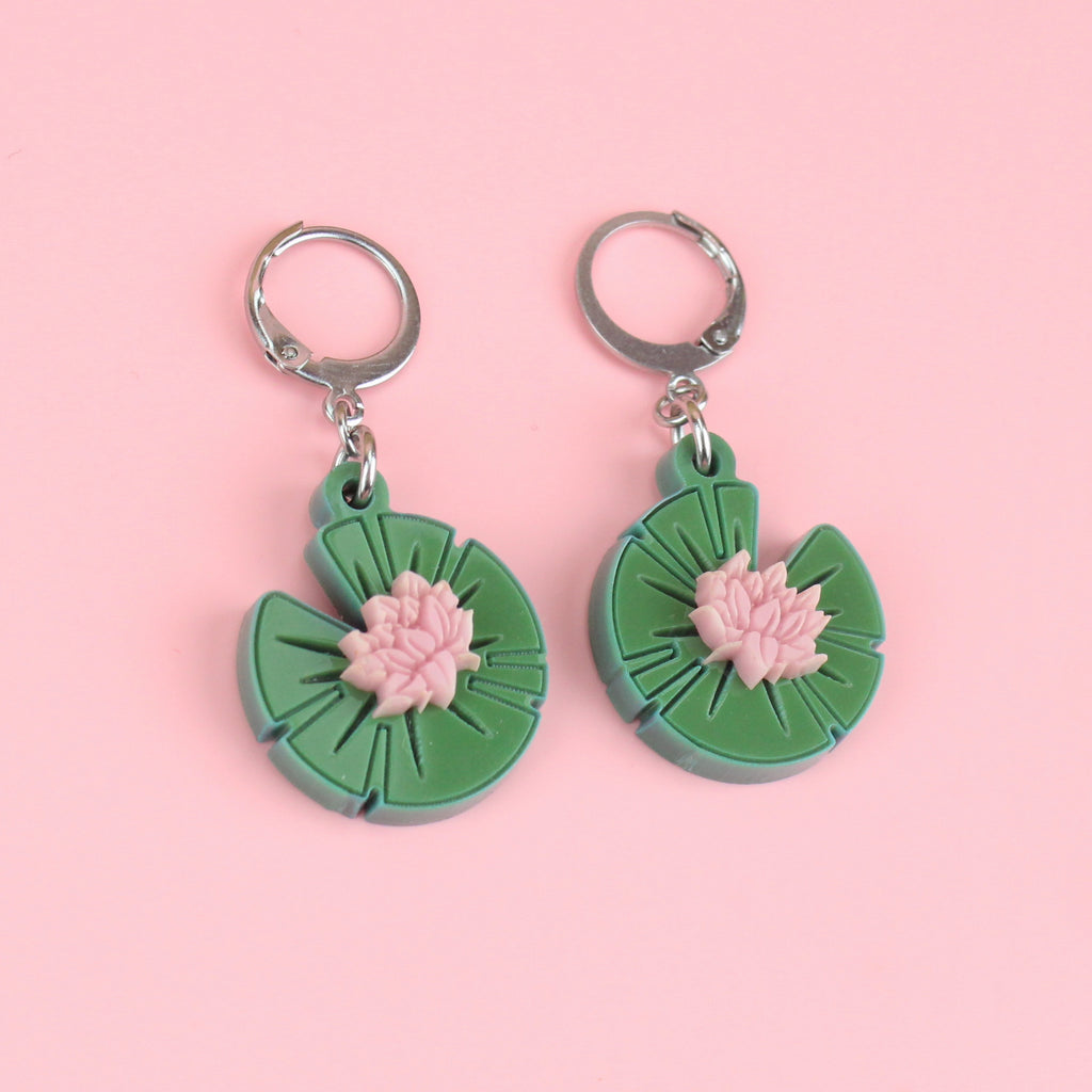 Green acrylic lily pad charms with a pink lotus flower in the centre on stainless steel huggie hoops