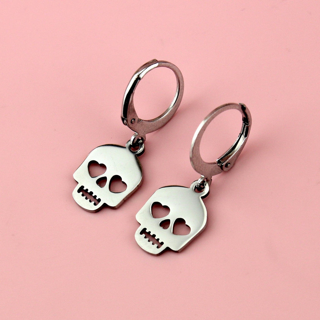 Stainless steel skull charms with cut out heart eyes on stainless steel hoops