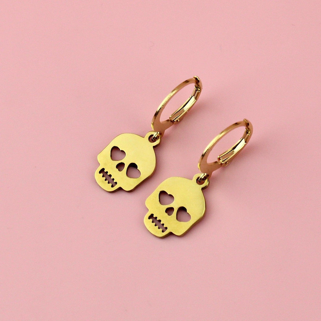 Gold plated skull charms with cut out heart eyes on gold plated stainless steel hoops