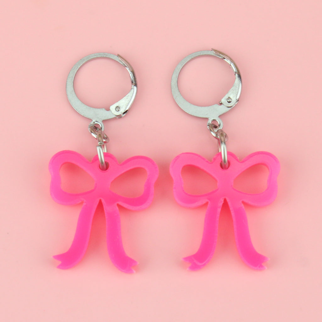 Bright pink mini bow charms on stainless steel huggie hoops