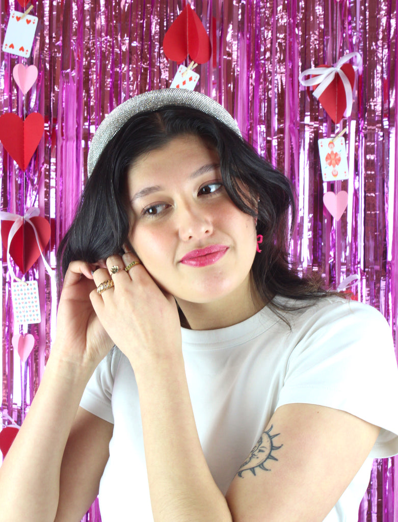 Model wearing Bright pink mini bow charms on stainless steel huggie hoops