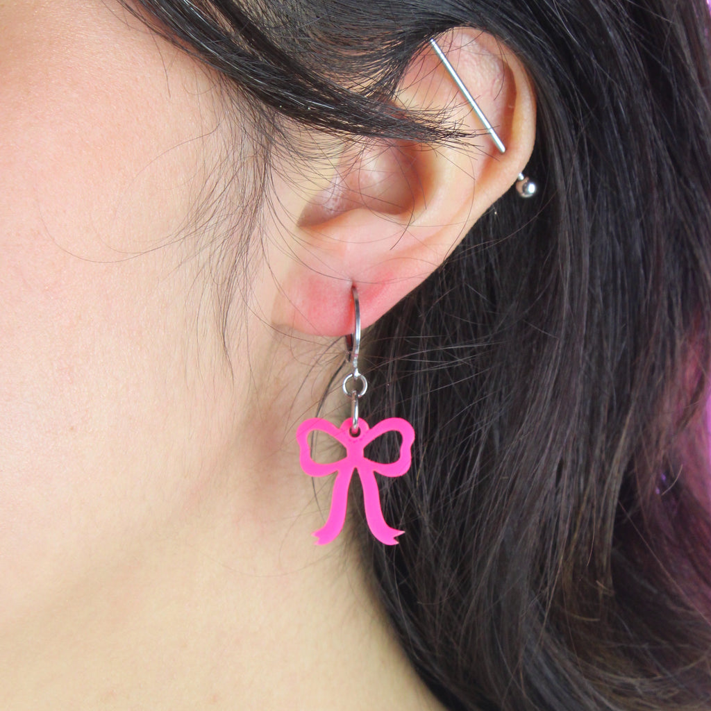 Bright pink mini bow charms on stainless steel huggie hoops
