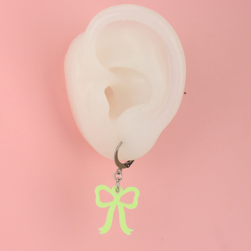 Ear wearing Green bow charms on stainless steel huggie hoops