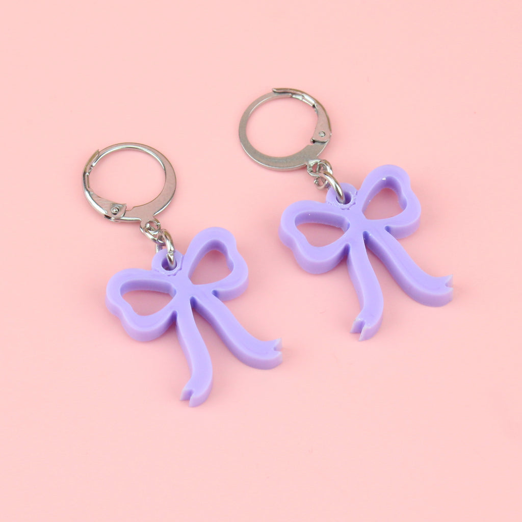 Lilac coloured bow charms on stainless steel huggie hoops
