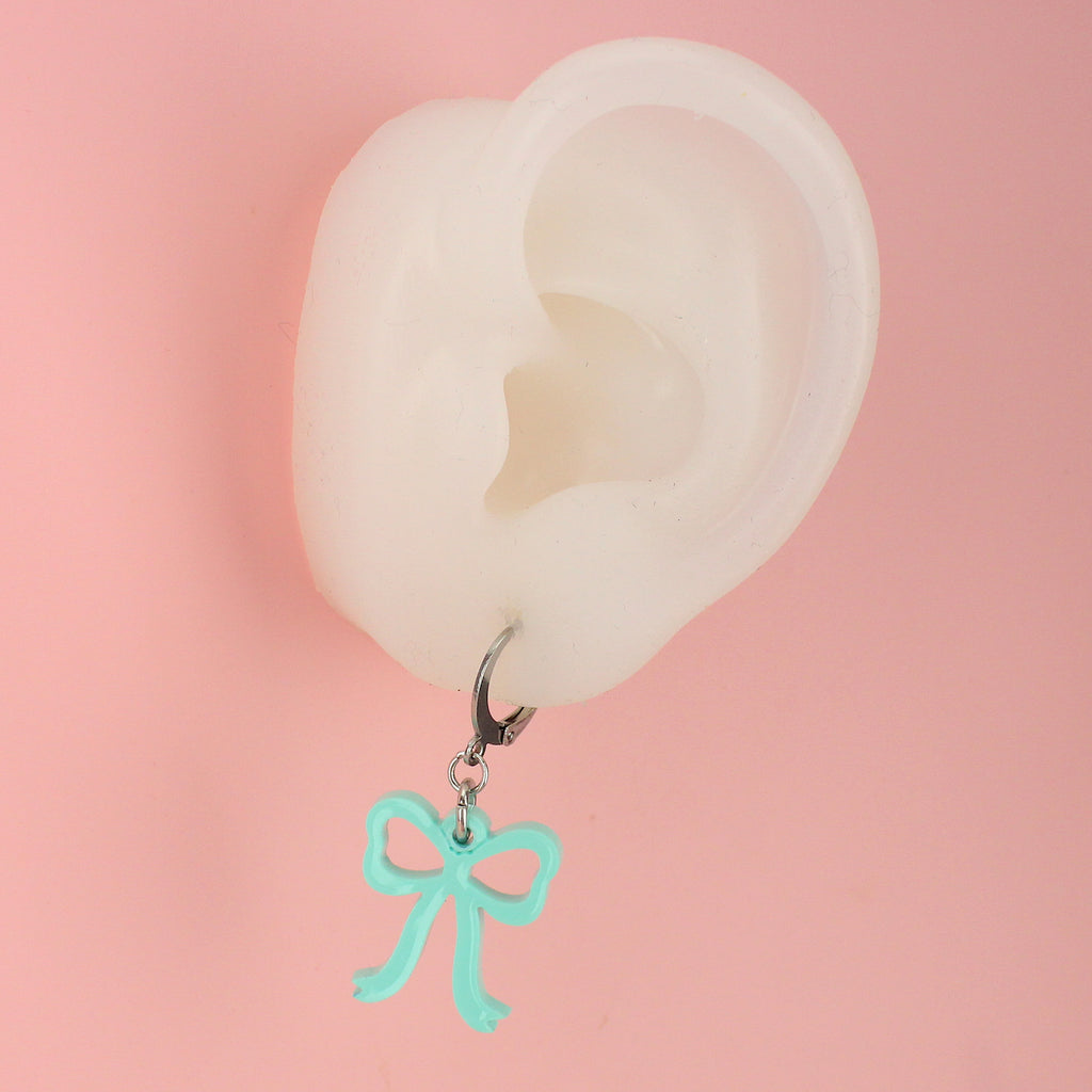 Ear wearing Turquoise bow charms on stainless steel huggie hoops