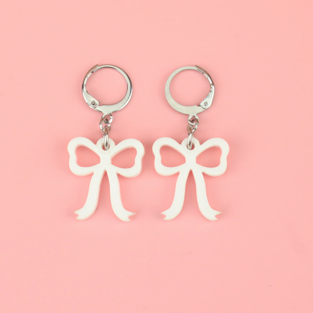 White bow charms on stainless steel huggie hoops