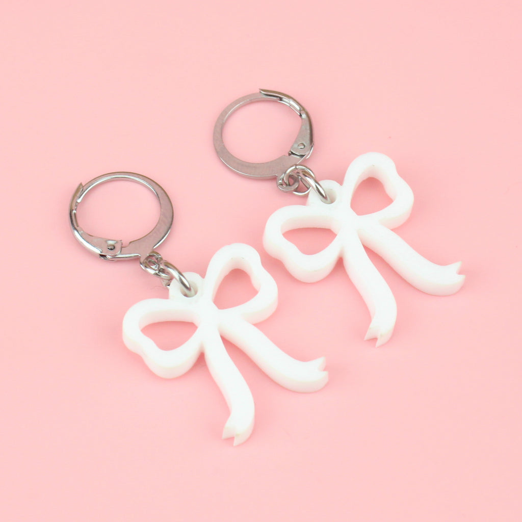 White bow charms on stainless steel huggie hoops