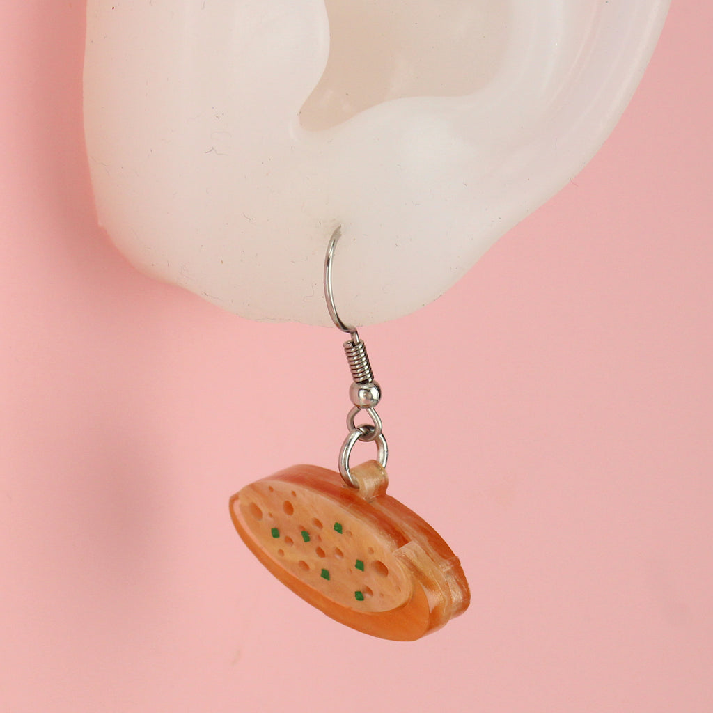 Ear wearing acrylic garlic bread on a stainless steel earwire