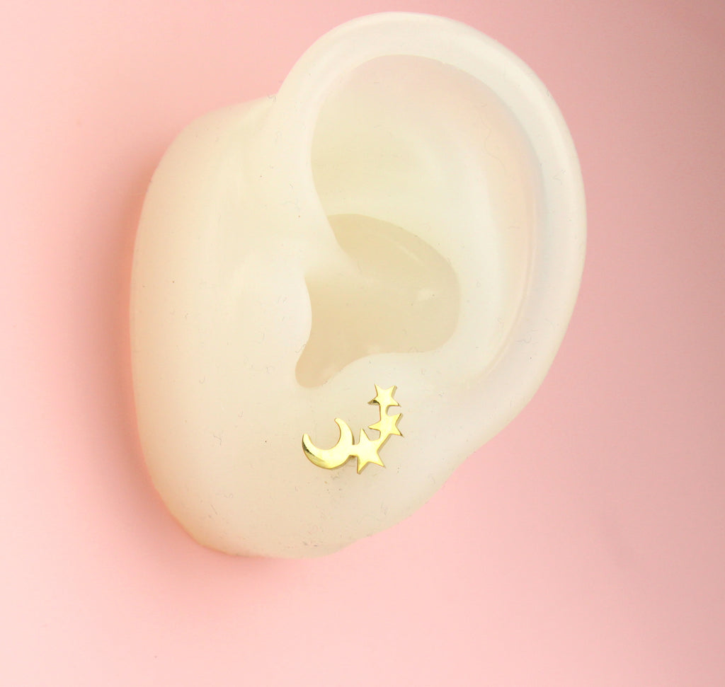 Ear wearing Gold plated stainless steel studs featuring a crescent moon and three stars