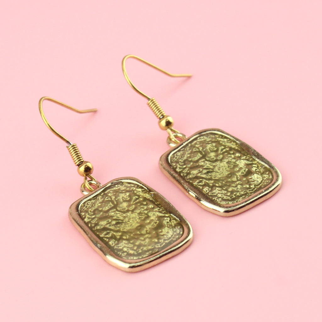 Gold rectangular shaped earrings with a wavy outline and a shimmery olive coloured centre
