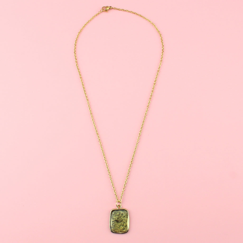 Gold rectangular shaped pendant with a wavy outline and a shimmery olive coloured centre on a gold plated stainless steel chain