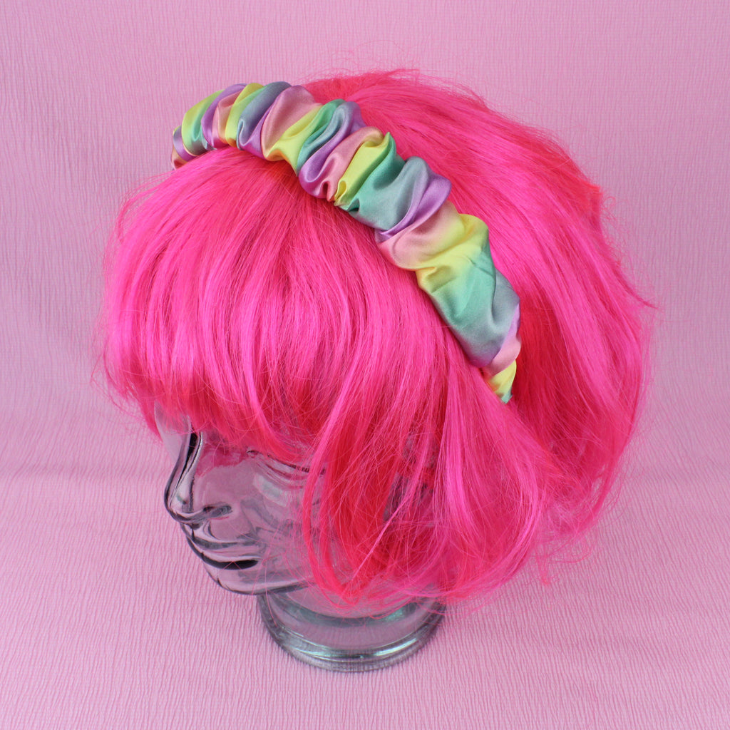 Satin scrunchie style headband with pastel yellow, pink, purple, green and blue colours, shown on a wig for scale
