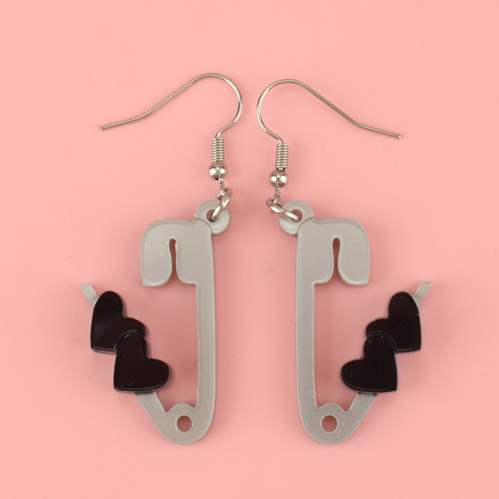Grey acrylic open safety pin style charms adorned with two black hearts on stainless steel earwires