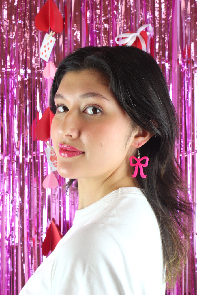 Model wearing Hot Pink Bow Charms on stainless steel earwires holding a dog with a red bow tie
