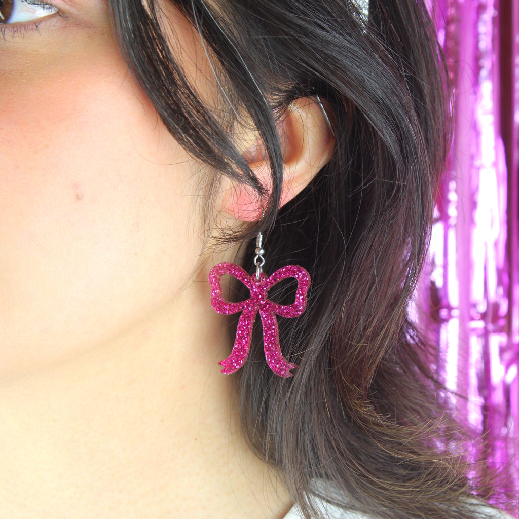 Model wearing Pink glitter bow charms on stainless steel earwires 