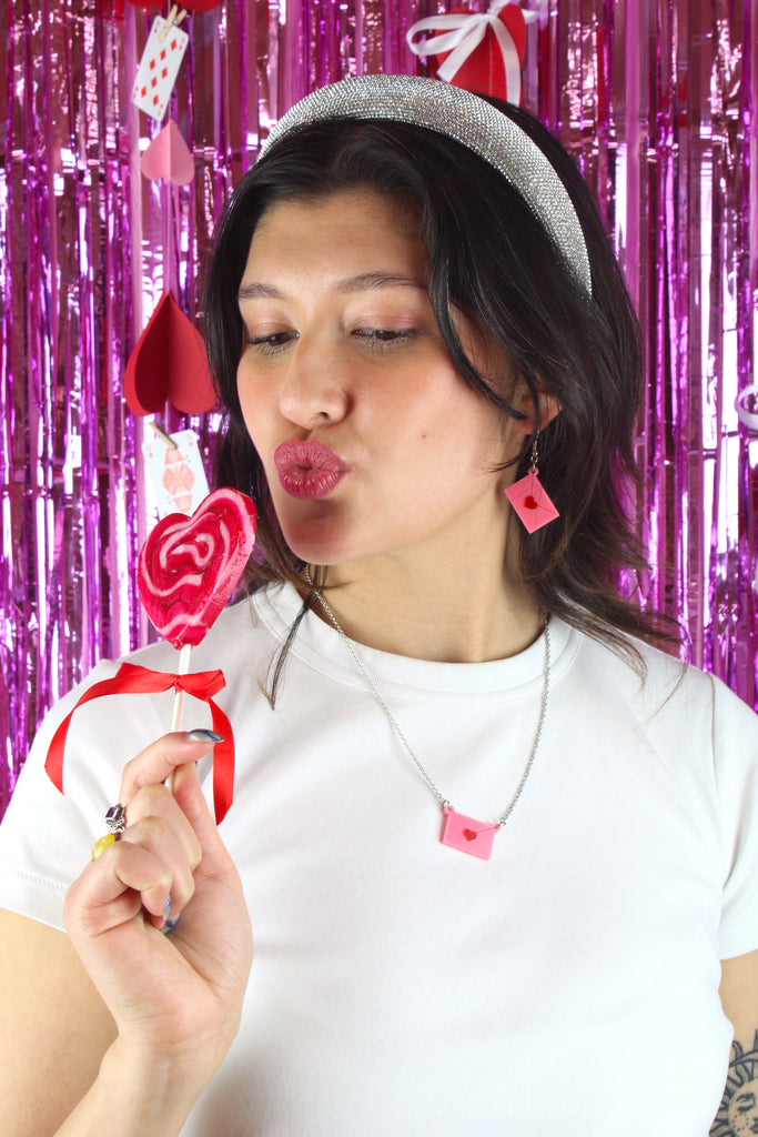 Model wearing acrylic pink envelopes, each sealed with a red heart, and attached to stainless steel earwires