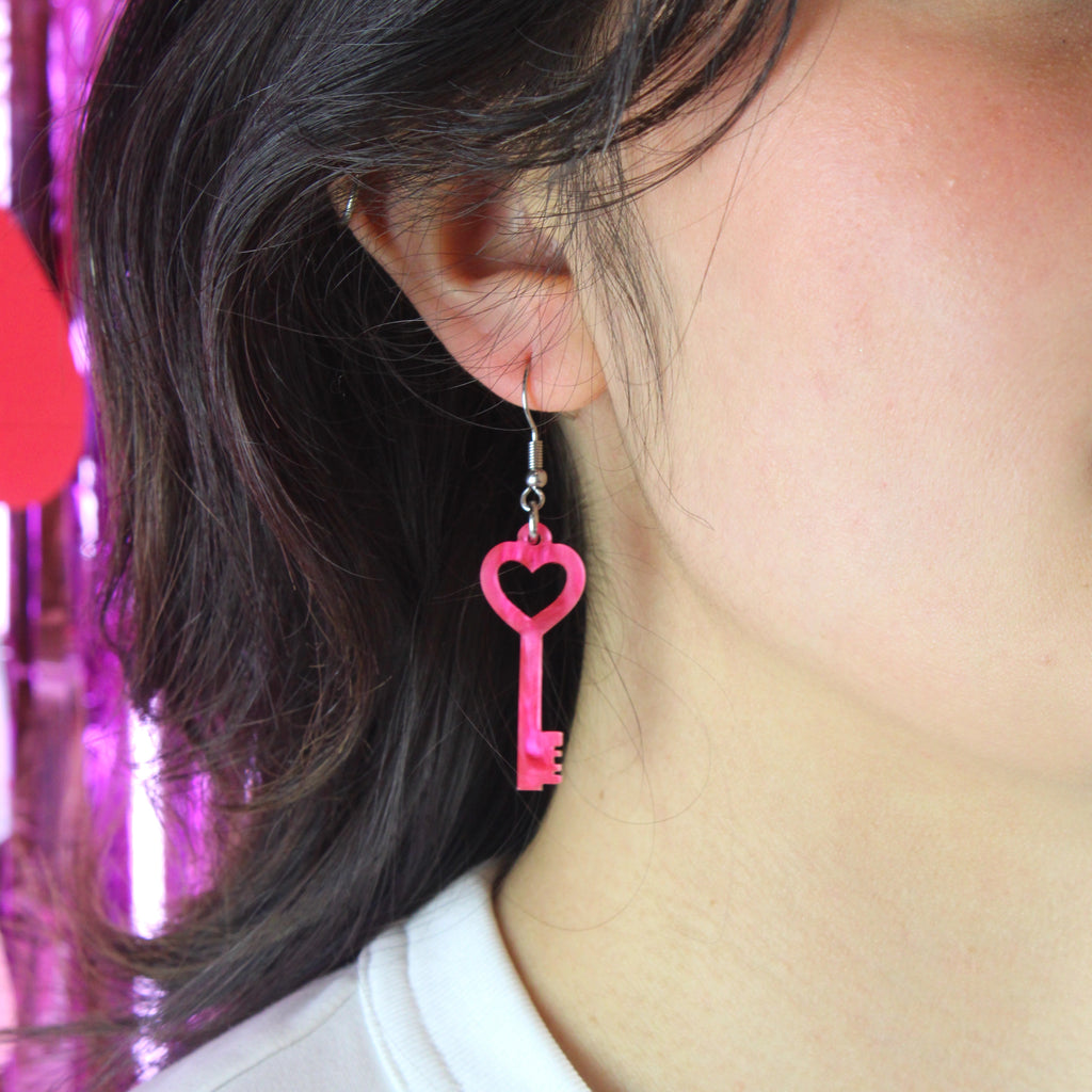Model wearing pink marble key charm on a stainless steel earwire