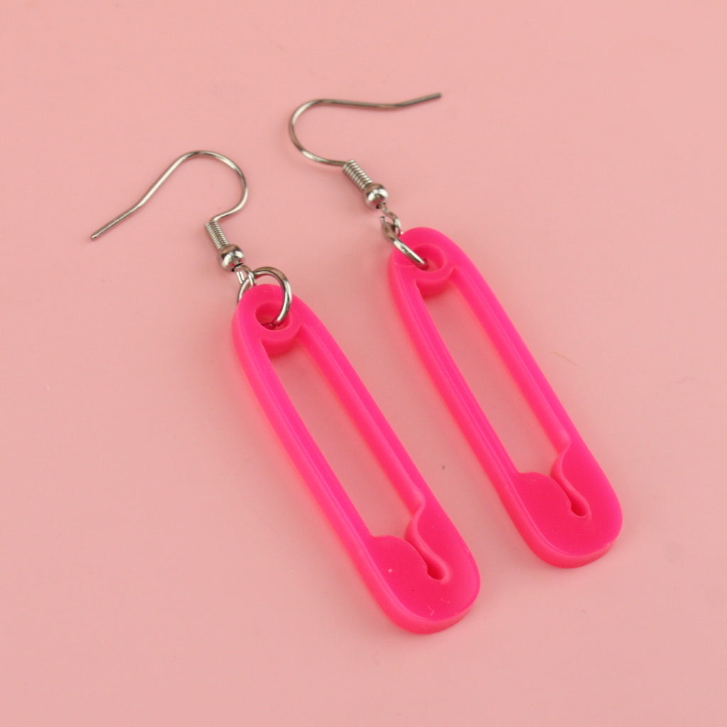 Neon pink acrylic charms in the shape of a safety pin on stainless steel earwires