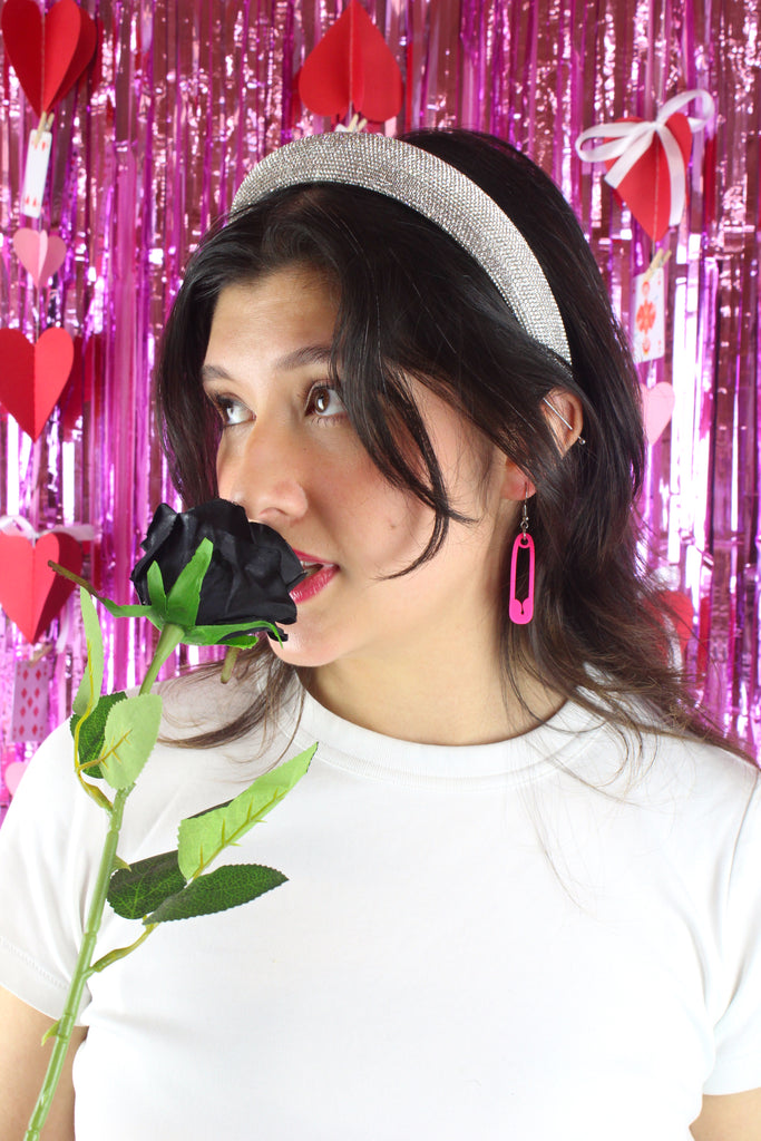 Model wearing a neon pink acrylic charms in the shape of a safety pin on stainless steel earwires
