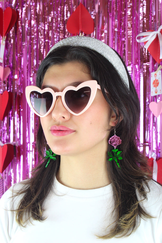 model wearing pink mirror acrylic roses and charming green acrylic thorn charms joined together hanging from stainless steel earwires