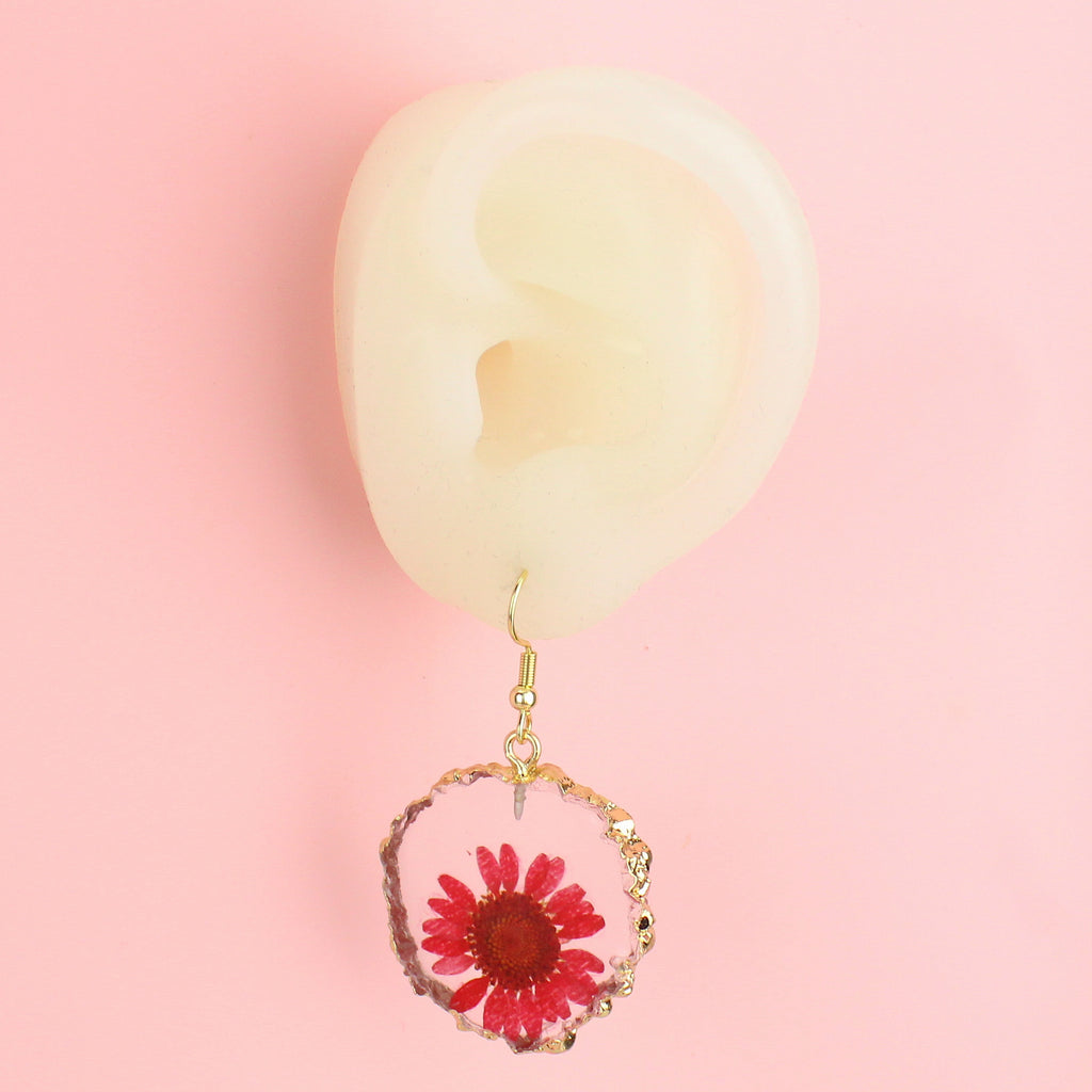 Ear wearing Pink pressed flowers earrings with a gold edge on gold plated stainless steel earwires