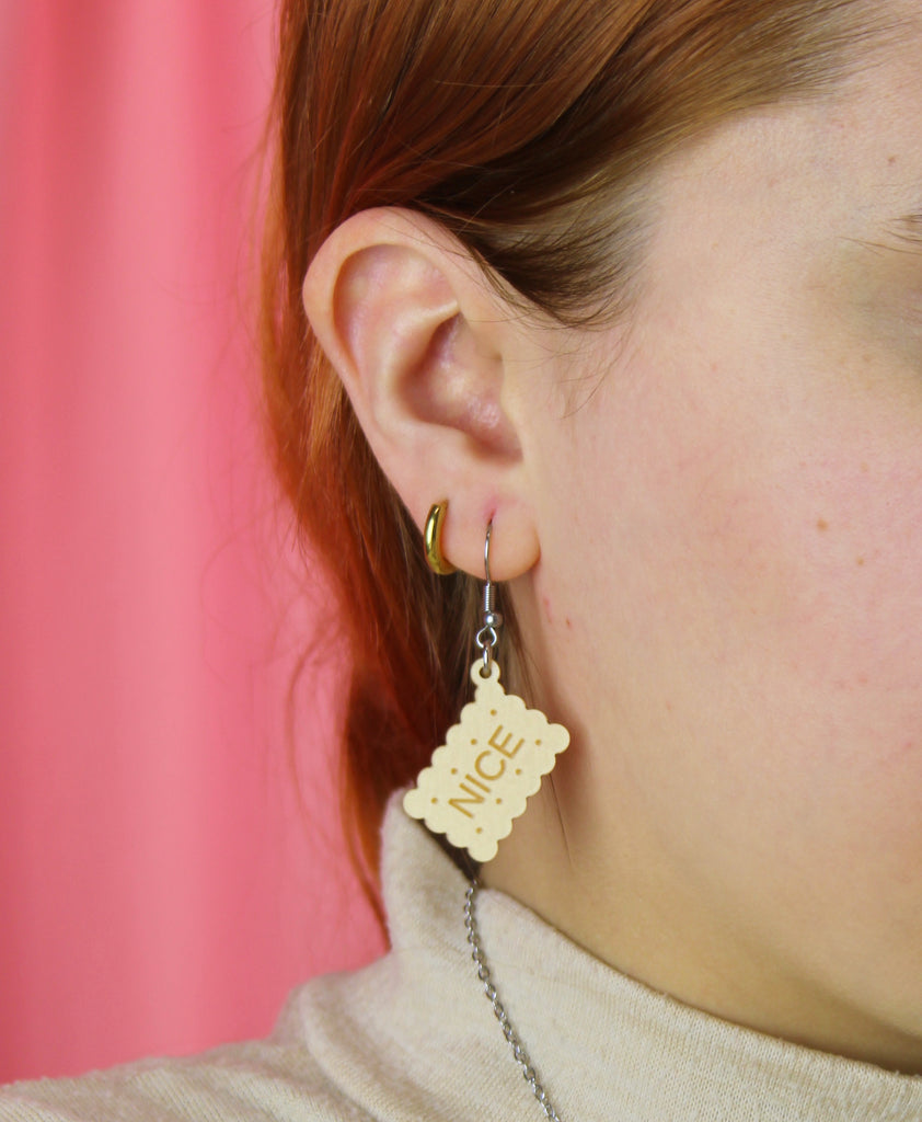Earrings with nice biscuit charms on a pink background, worn by model