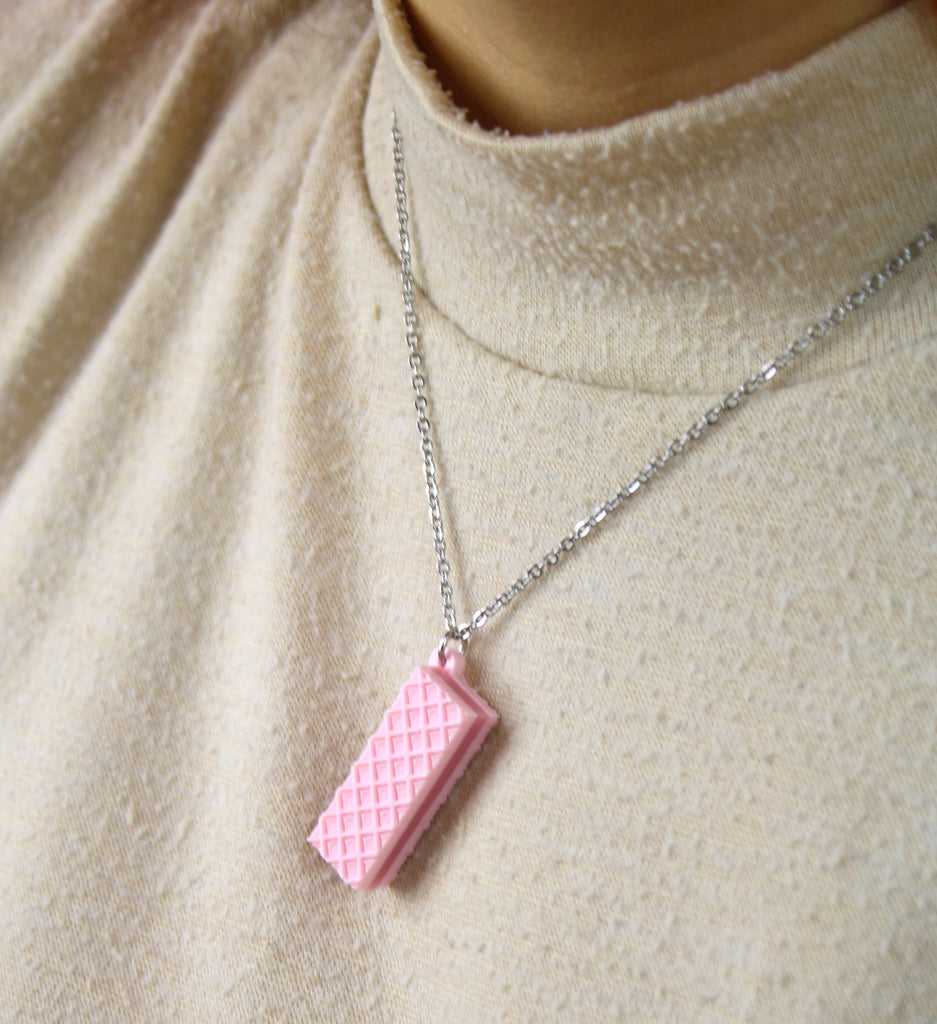 Necklace with a pink wafer pendant on a beige sweater