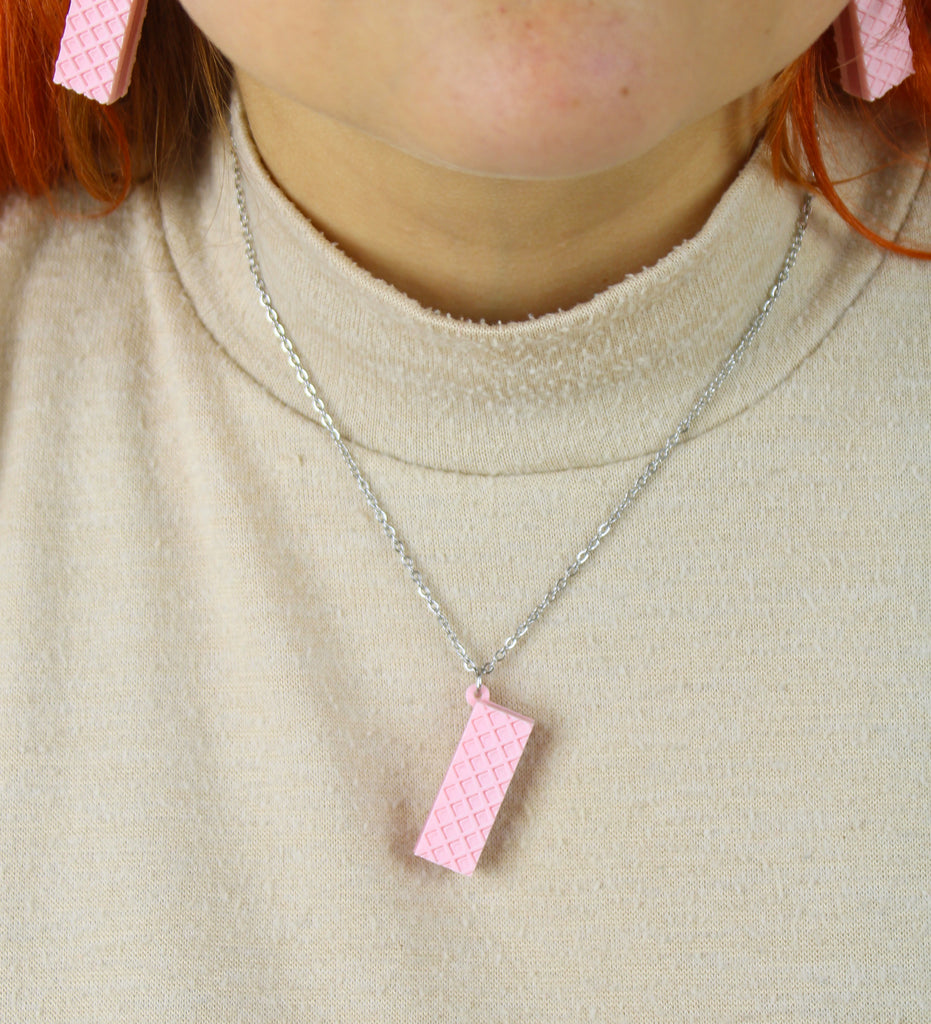 Person wearing a necklace with a pink wafer  pendant