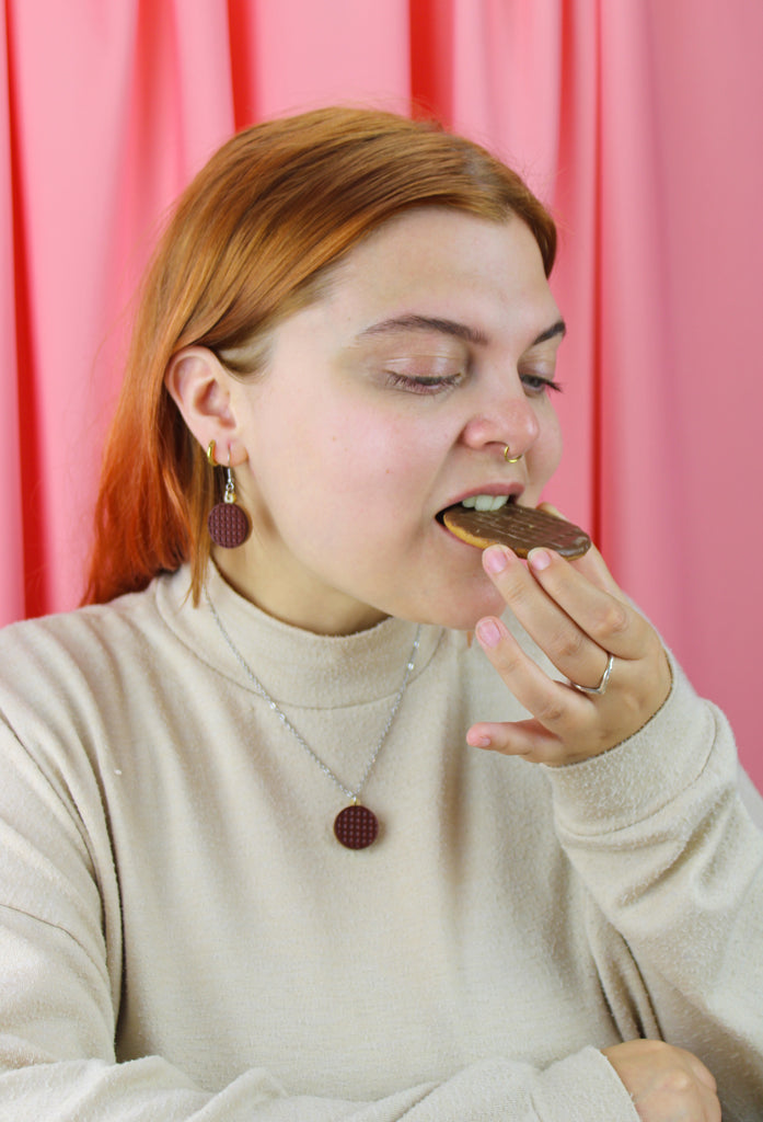 Woman eating a cookie against a pink curtain background