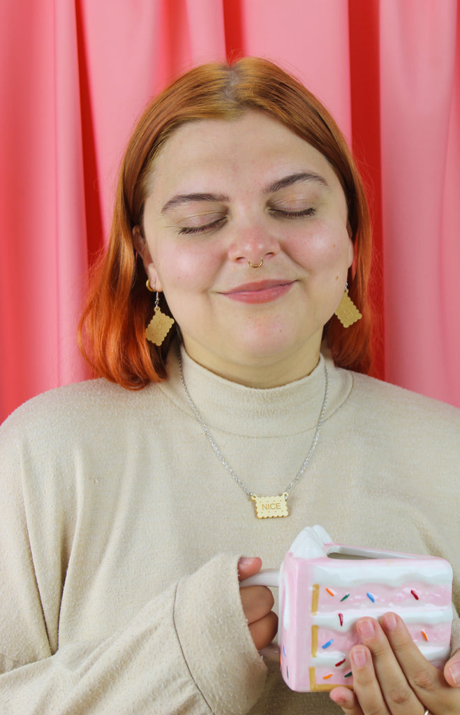 Woman holding a mug against a pink curtain