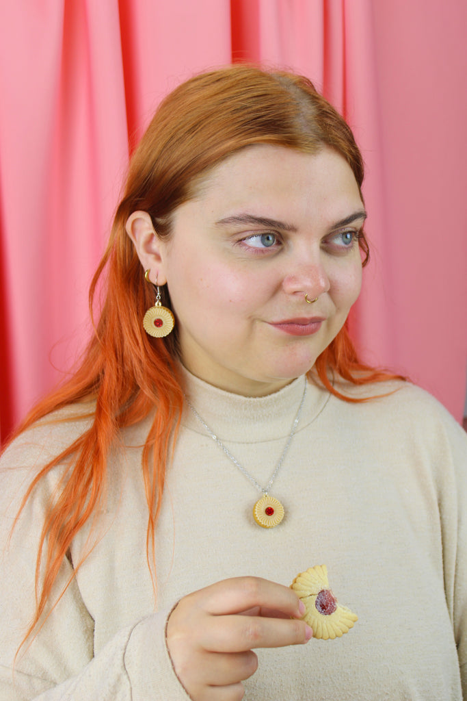 Necklace featuring a pendant of a jam and cream biscuit, worn by model